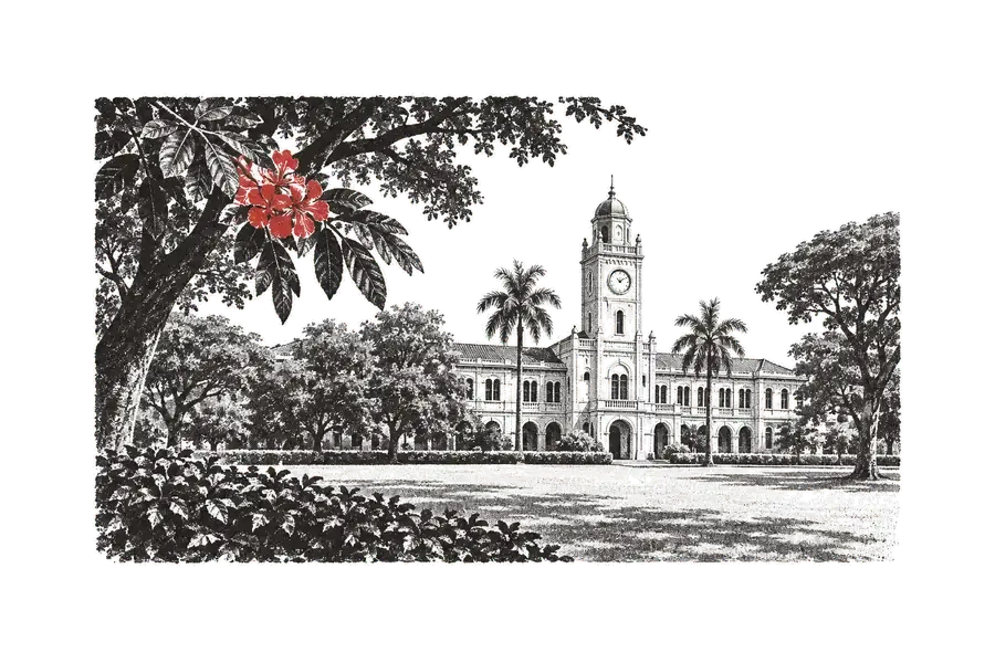 A university building with a clock tower, seen from the lawn under trees; a bunch of red flowers in the foreground.